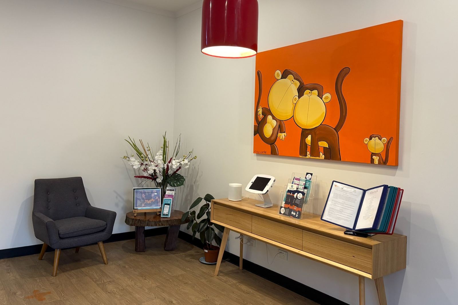 The Bright Buds reception area with a sign-in kiosk, armchair and a bright orange artwork